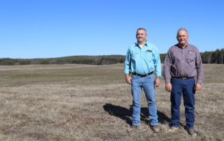 Danny and Jon Shaw stand in a field with blue sky behind.