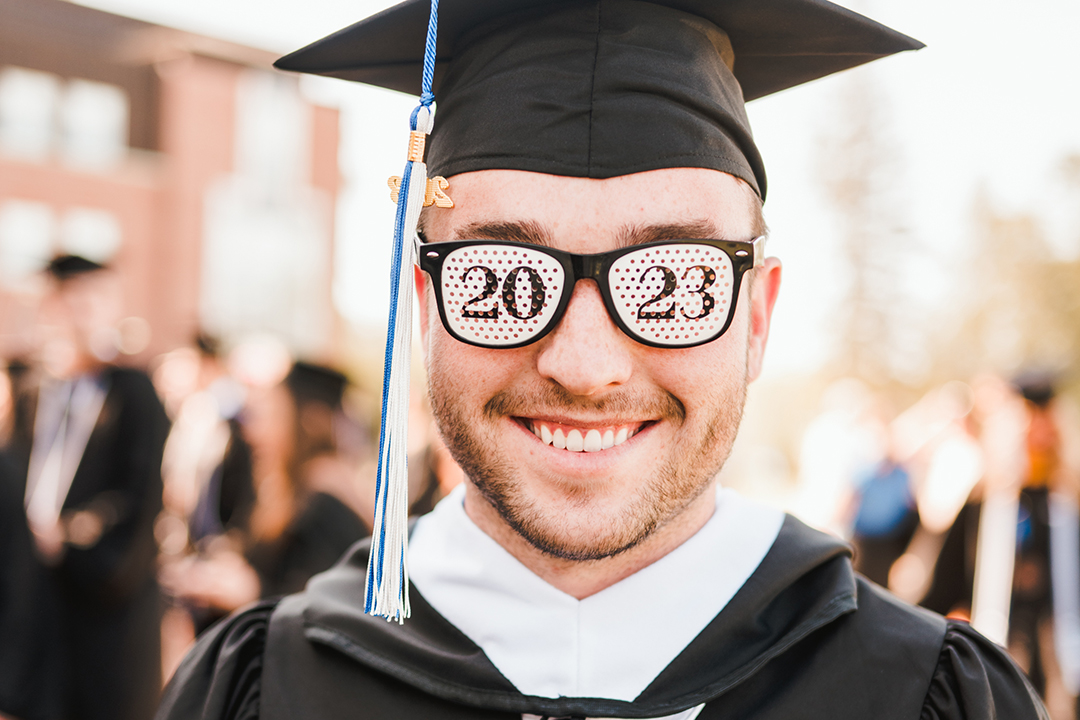 A male graduate wears 2023 sunglasses.