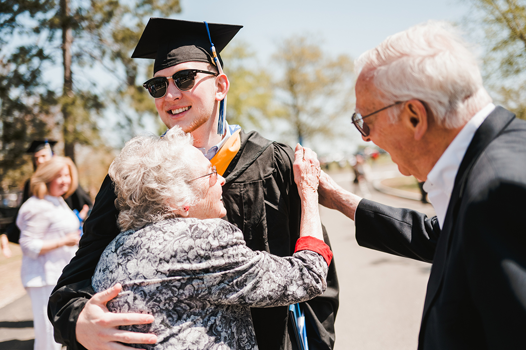 A graduate gets congratulated by his grandparents.