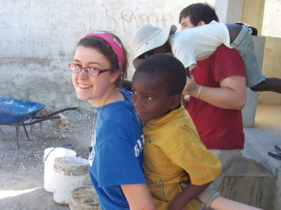 Nursing student in Haiti carrying a child