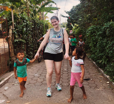 Kelly in Guatemala on service trip holds the hands of local children