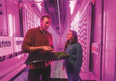 Mark Green holds seedling and talks to Emily Quirion '18 in the Freight Farm
