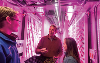 Professor Mark Green converses with students inside a bright pink shipping container.