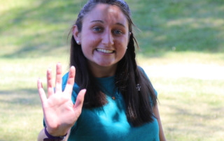 MaryClaire holds her hand out in a high-five, which is the logo for SJC Peer Mentors