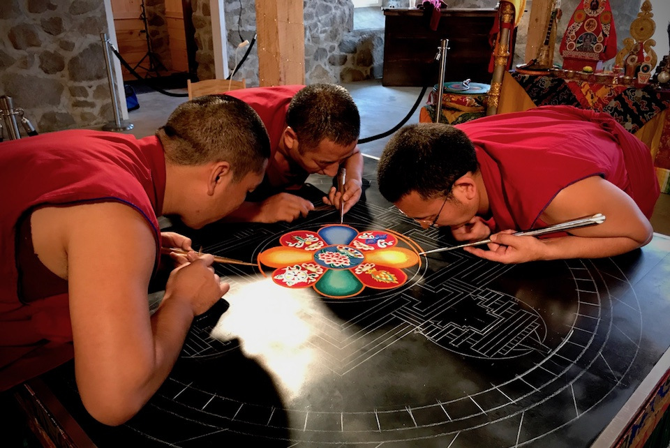 Tibetan Buddhist monks paint a colorful mandala.