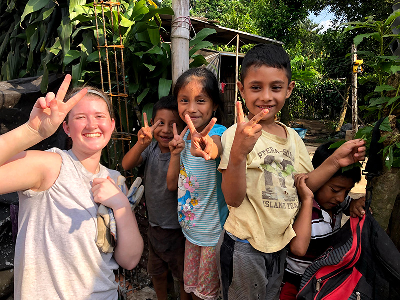 Kelly in Guatemala and local children give the peace sign