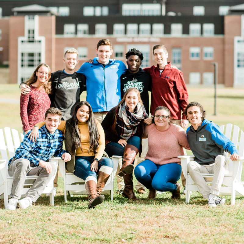Saint Joseph's College of Maine campus students in the fall in front of Alfond Hall