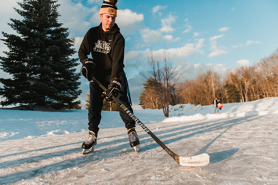 Student playing hockey on the pond