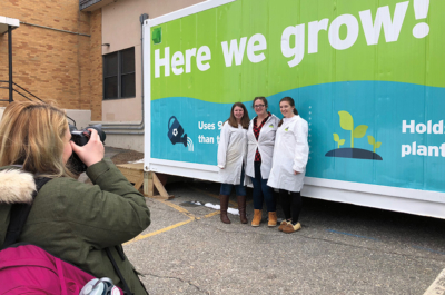 Kaitlynn Hutchins ‘19 photographs fellow students outside of the Leafy Green Machine TM manufactured by Freight Farm.