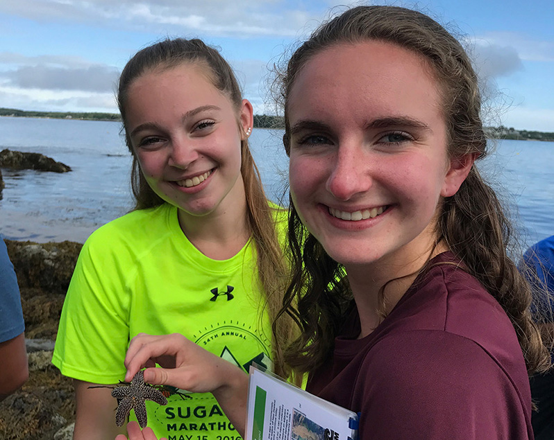 STEM students hold a starfish during a field trip to the nearby ocean